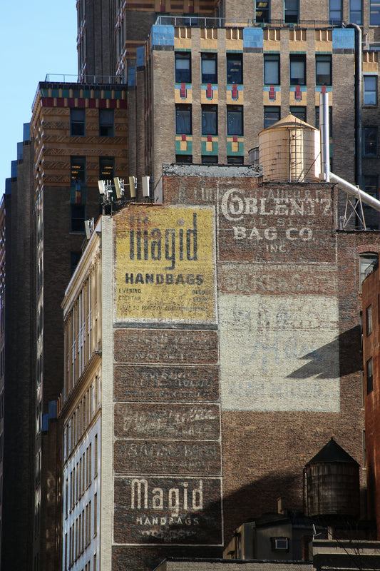 Old brick buildings with vintage advertisements for handbags.